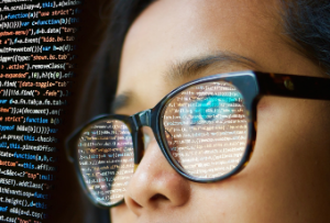 Woman writing code with reflection in glasses