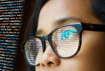 Woman writing code with reflection in glasses