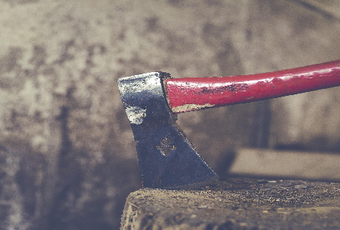 A red-handled axe resting on a wooden chopping block