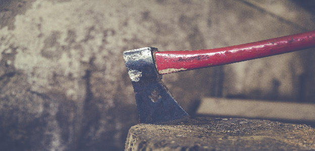 A red-handled axe resting on a wooden chopping block